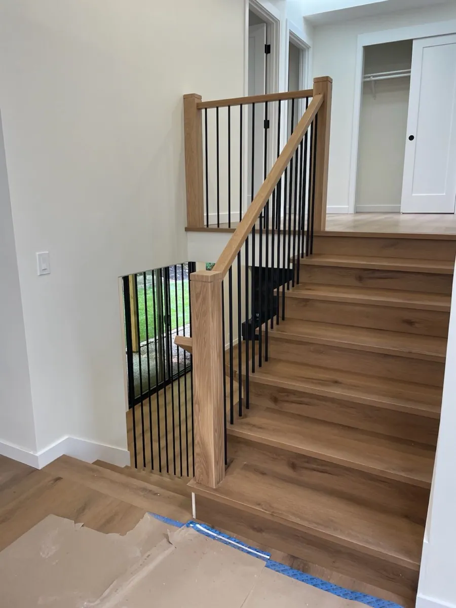 Custom warm oak staircase with black metal railing in a Seattle home